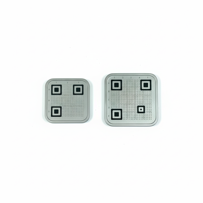 Two square metallic objects with black square patterns on a white background